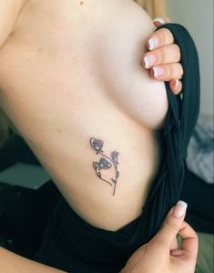 a close up of a person's breast with a flower tattoo on her left side