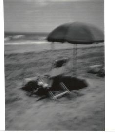 black and white photograph of beach chair with umbrella