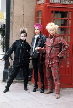 three mannequins dressed in costumes standing next to a telephone booth