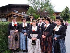 a group of women standing next to each other in front of a building and trees