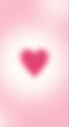 a blurry pink background with a heart shaped object