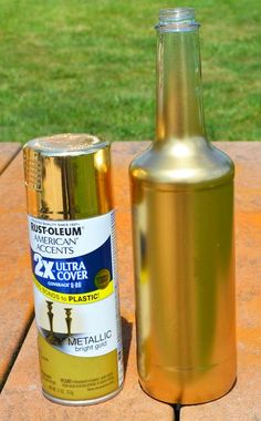 an empty bottle next to a metal can on a picnic table in the sun outside