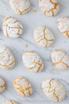 several different types of powdered sugar cookies on a white marble counter top with crumbs