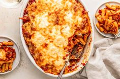 a casserole dish with pasta and sauce on the side, next to other dishes