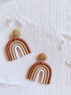 two wooden earrings with rainbows on them sitting on top of a white cloth covered surface