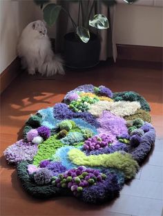 a cat sitting on the floor in front of a rug made out of yarns