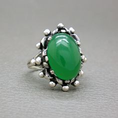 A dramatic design antique Biedermeier Victorian style ring. A large green chrysoprase cabochon is set in a beautifully hand crafted solid silver setting. The ring will be shipped in a gift box. Green Chrysoprase is a variety of chalcedony, which is a type of quartz, and is one of the more valuable stones of this group. Chrysoprase is known as a traditional birthstone of May. Ring size: 10 (US) / T 1/2 (UK) / diameter 19.8 mm / European size: 62 1/4 - it is a big size ring Ring face measures over Heirloom Green Emerald Oval Cabochon Ring, Heirloom Green Oval Cabochon Emerald Ring, Heirloom Green Oval Cabochon Rings, Heirloom Green Jade Rings, Antique Green Oval Cabochon Ring, Antique Green Turquoise Ring As Gift, Green Rings With Large Oval Cabochon Stone, Green Oval Cabochon Ring With Large Stone, Vintage Green Turquoise Cabochon Ring