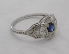 an antique style ring with blue and white stones on the sides, set in silver