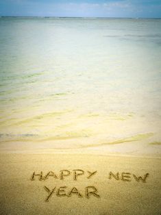 happy new year written in the sand at the beach