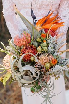 a bride holding a bouquet of flowers and succulents