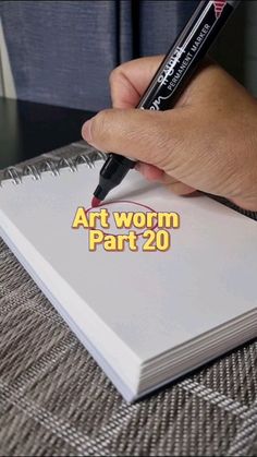 a person is writing on a book with a pen in their hand and the words art wormm part 20 written below it