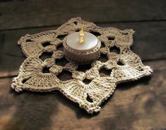 a crocheted doily with a candle on it