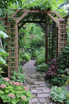 a garden with lots of flowers and plants around the area, along with a stone path