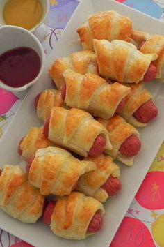 hotdogs wrapped in crescent rolls on a plate with dipping sauce