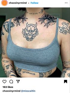 a woman with lots of tattoos on her chest and arms, wearing a gray tank top