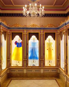 an empty room with three dresses on display in the windows and chandelier hanging from the ceiling