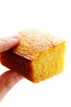 a hand holding a piece of yellow cake