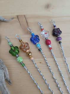 six different colored glass bead necklaces on a wooden table next to a piece of driftwood