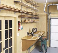 a workbench in a garage with tools on the table and shelves above it