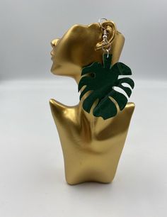 a pair of gold earrings with a green leaf hanging from it's earring