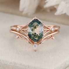 a close up of a ring with a green stone in it on a white surface