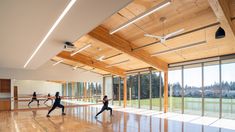 people are doing yoga in an empty room with large windows and wood floors, while the ceiling is made of wooden planks