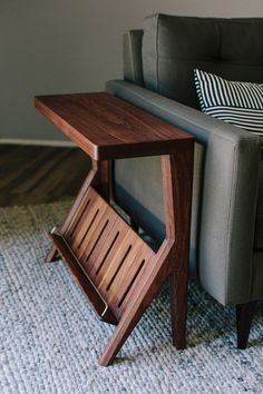 a couch with a wooden side table next to it on carpeted flooring in front of a gray sofa