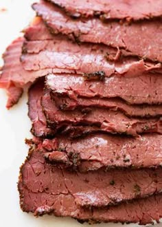 sliced meat sitting on top of a white cutting board