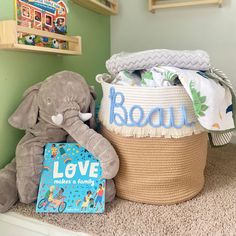 a stuffed elephant sitting next to a basket filled with books and other children's toys