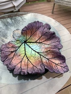 a purple leaf is sitting on top of a glass table