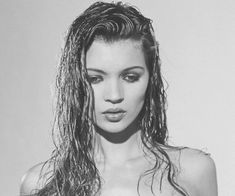 a black and white photo of a woman with wet hair looking at the camera while wearing a bra