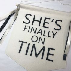 she's finally on time sign hanging from a string with ribbon around it and the words, she's finally on time