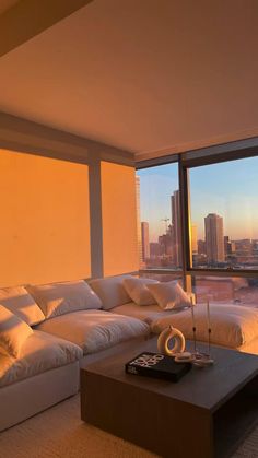 a living room filled with furniture and large windows overlooking the cityscape in the distance