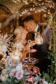 a bride and groom kissing in front of an array of desserts