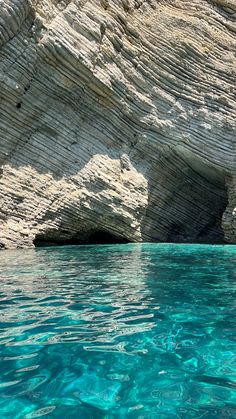 the water is crystal blue and there are some rocks in the backgrouds