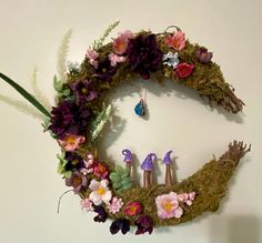 a wreath made out of moss and flowers with three little birds on the top one