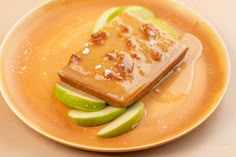 a piece of cake on a plate with apples and caramel drizzled around it