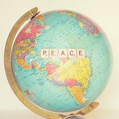 a small globe with the word peace written on it, sitting on a white surface