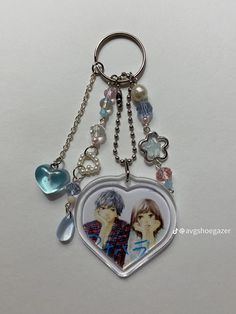 a heart shaped keychain with two people on it and charms hanging from the front