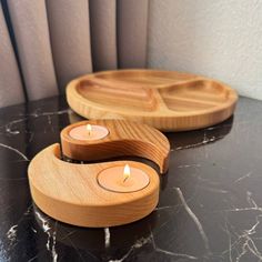 two wooden trays sitting on top of a table with lit candles in each one