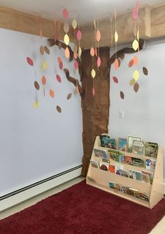 there is a book shelf with many books on it in front of a wall decorated with paper leaves