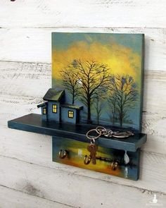 a painting on a shelf with a key hanging from it's side and a house in the background