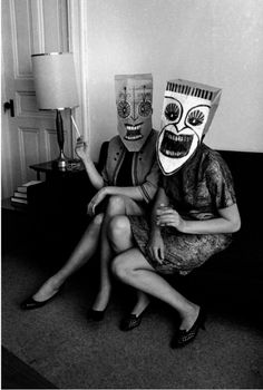 two people wearing masks sitting on a couch