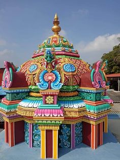 an elaborately painted building on the side of a road with palm trees in the background