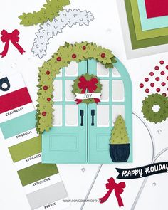 a close up of a christmas card with a door and wreath on the front, surrounded by other cards