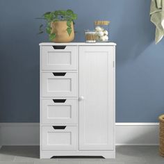 a white cabinet with five drawers in a blue room next to a potted plant