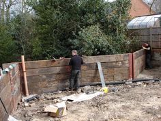 two men are working on a wooden fence