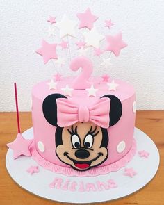 a pink birthday cake with minnie mouse on it's face and stars around the top