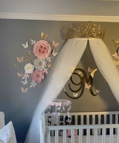 a baby's room decorated in gold and white with pink flowers on the wall