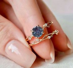 a close up of a person's hand with a ring on it and a blue stone in the middle